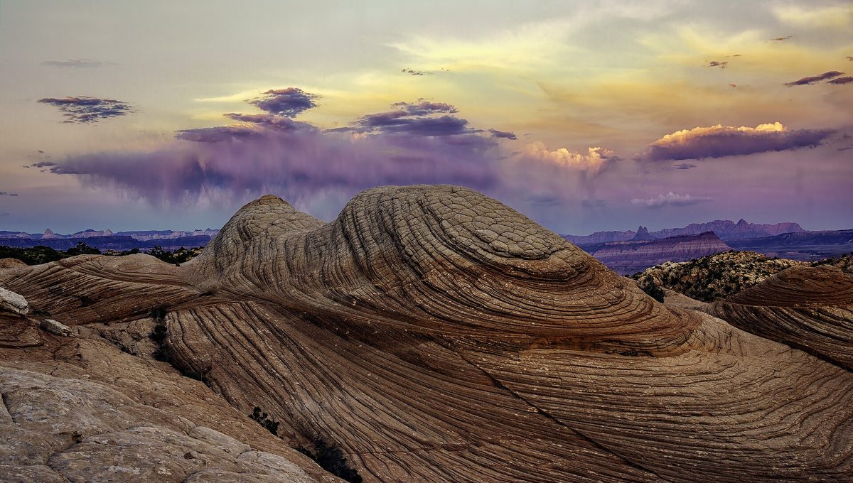 A rocky ridge above a valley lit by a low evening sky.