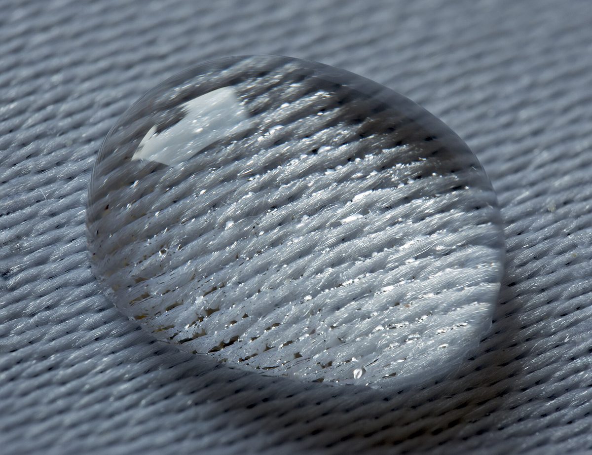 A water droplet beading on the surface of a woven fabric.