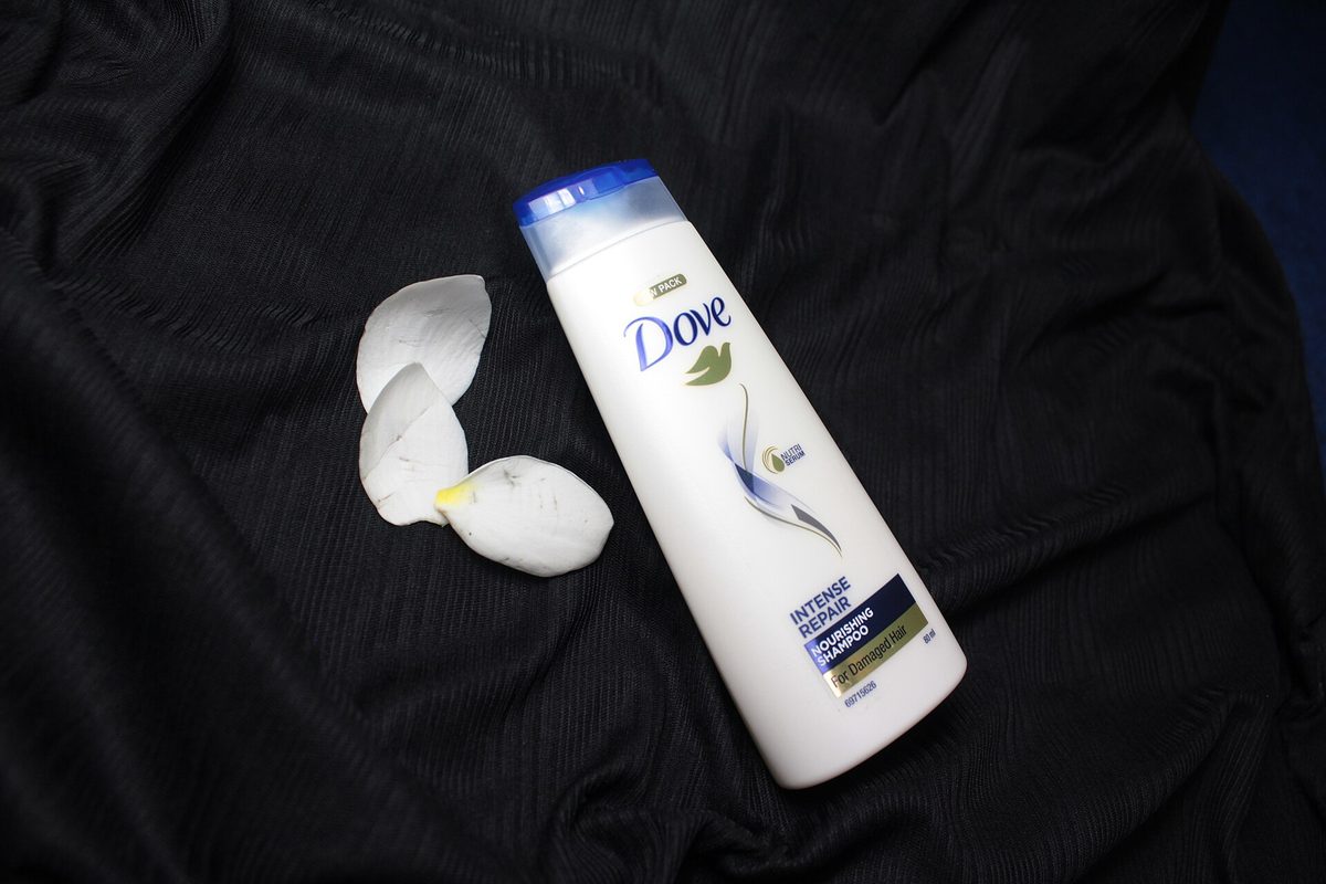 A travel-size bottle of shampoo photographed on a dark background.